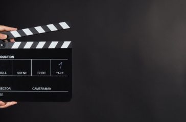 Hand is holding Black clapperboard or movie slate on black background.It have write in number.