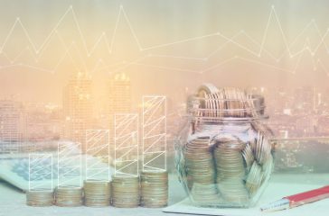 Double exposure of Graph on stack of coins money and the glass bottle on city background, investment and business concept