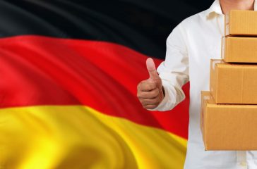 Germany real estate sale concept. Wooden house model with discount tag on national flag background. Copy space for text.
