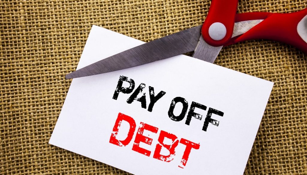Handwriting text showing Pay Off Debt. Conceptual photo Reminder To Paying Owed Financial Credit Loan Bills written on Sticky Note Paper Cutting by Scissors on the textured background