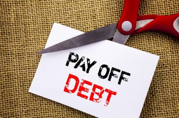 Handwriting text showing Pay Off Debt. Conceptual photo Reminder To Paying Owed Financial Credit Loan Bills written on Sticky Note Paper Cutting by Scissors on the textured background