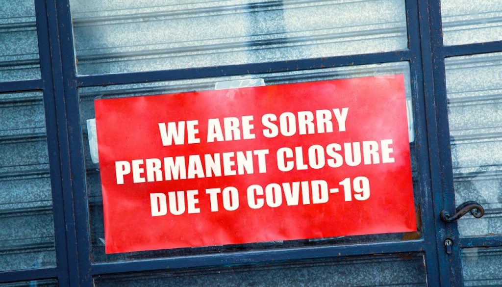Red closed sign in the window of a shop displaying permanent closure