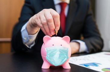 Businessman putting money in a masked piggy bank