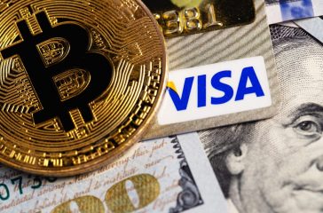 bitcoin cryptocurrency with Visa credit card and dollars, money. Visa - American multinational company providing services of payment operations. Moscow, Russia - August 16, 2020