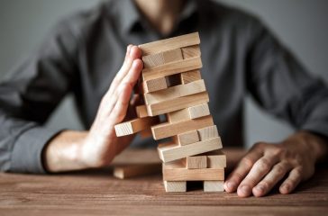 Businessman holds the model of business, made from wood blocks. Alternative risk concept, business plan and business strategy. Insurance concept.