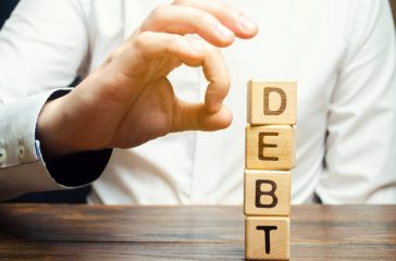 Businessman removes wooden blocks with the word Debt. Reduction or restructuring of debt. Bankruptcy announcement. Refusal to pay debts or loans and invalidate them. Debts service relief
