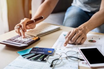 Young woman checking bills, taxes, bank account balance and calculating credit card expenses at home