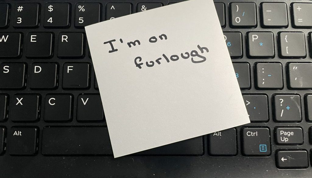 A handwritten note stating I'm on furlough on a computer keyboard