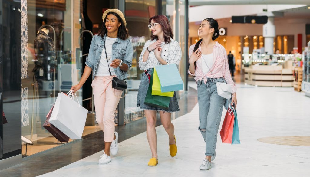 Stylish young smiling women walking with shopping bags, young gi