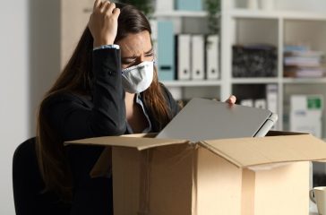 Fired executive with mask packing belongings at night