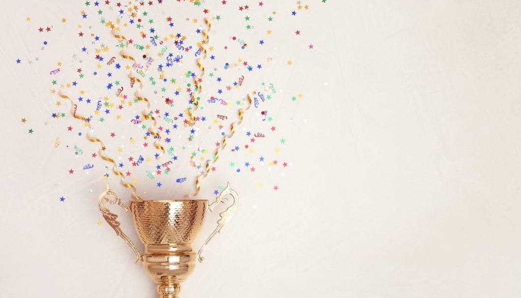 Trophy and confetti on light background, top view with space for