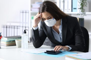Worried bookkeeper with mask looking at calculator